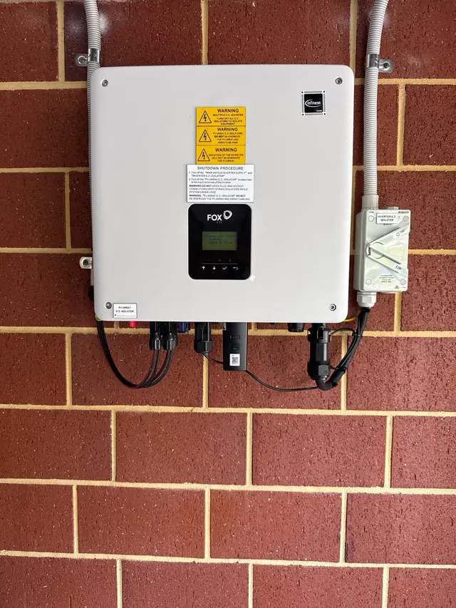 Fox ESS inverter installed on a red brick wall